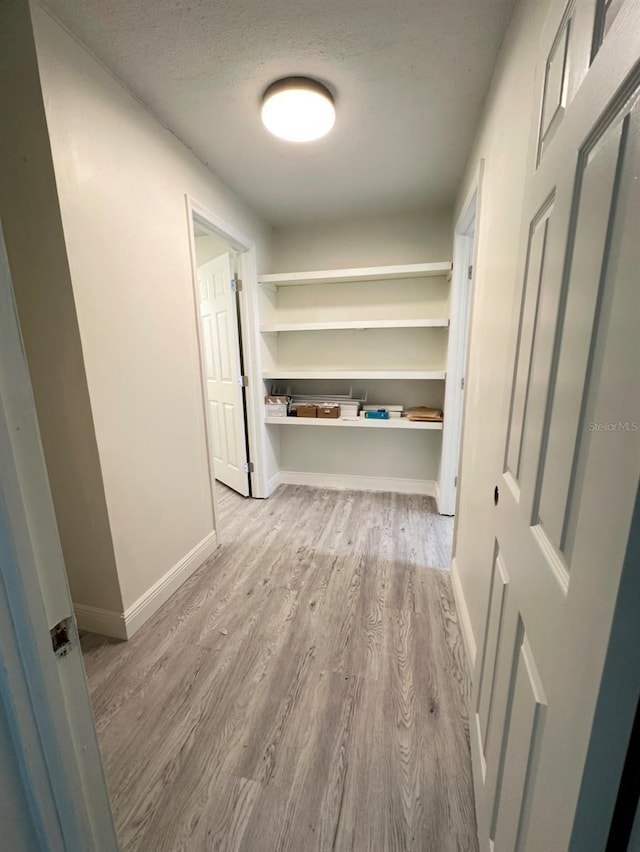 hallway with light hardwood / wood-style floors and a textured ceiling