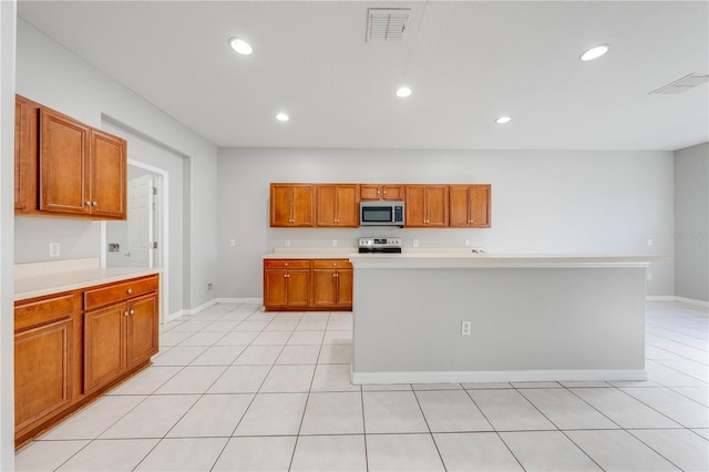 kitchen with an island with sink, light tile patterned floors, and appliances with stainless steel finishes