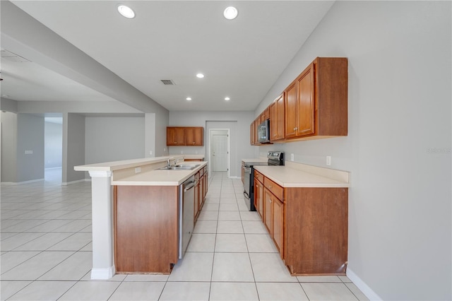 kitchen with a kitchen bar, sink, light tile patterned floors, and stainless steel appliances