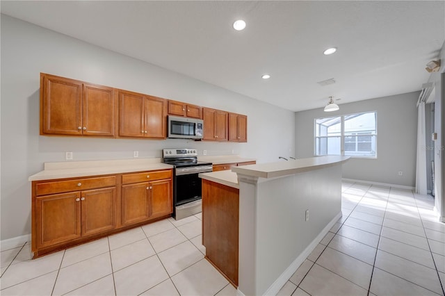 kitchen featuring a kitchen island, light tile patterned floors, stainless steel appliances, and hanging light fixtures