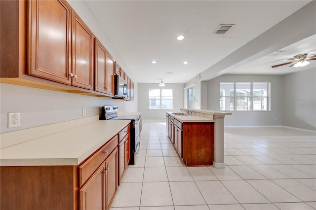 kitchen with ceiling fan, sink, a kitchen island with sink, light tile patterned flooring, and appliances with stainless steel finishes