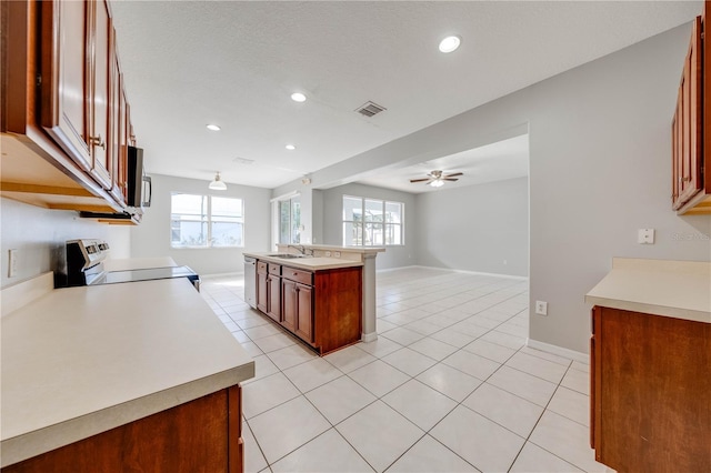 kitchen with stainless steel appliances, ceiling fan, a healthy amount of sunlight, and an island with sink