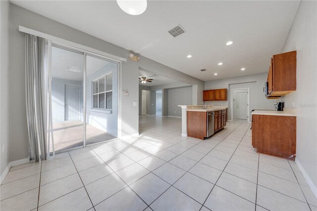 kitchen featuring ceiling fan, a kitchen island, light tile patterned flooring, and appliances with stainless steel finishes