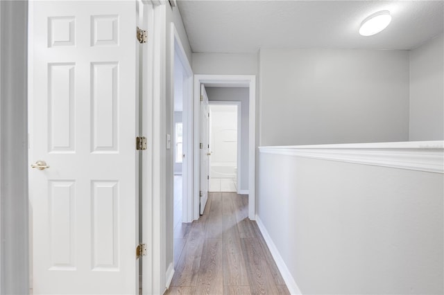 corridor with light hardwood / wood-style floors and a textured ceiling