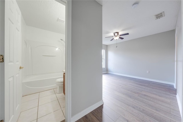 bathroom with bathtub / shower combination, hardwood / wood-style floors, toilet, and ceiling fan