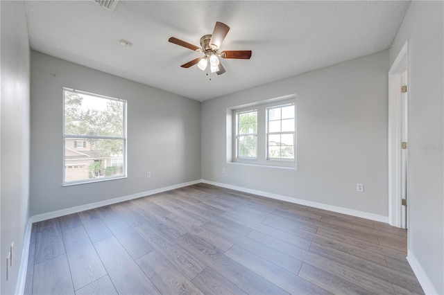 empty room with ceiling fan, light hardwood / wood-style floors, and a textured ceiling