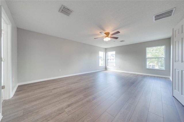 spare room with a textured ceiling, light hardwood / wood-style flooring, and ceiling fan