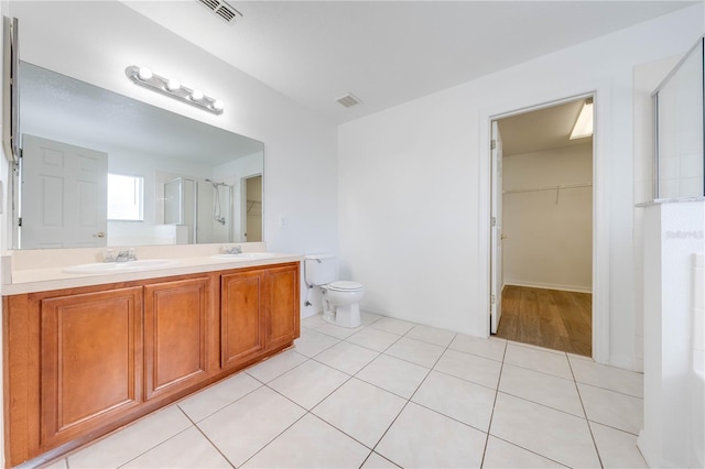 bathroom featuring toilet, vanity, tile patterned floors, and an enclosed shower