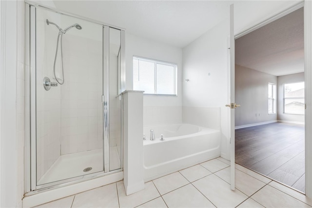 bathroom with tile patterned flooring, independent shower and bath, and a wealth of natural light