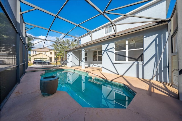 view of pool with glass enclosure, a patio area, and an in ground hot tub