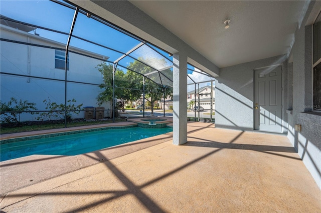 view of swimming pool featuring glass enclosure, an in ground hot tub, and a patio area