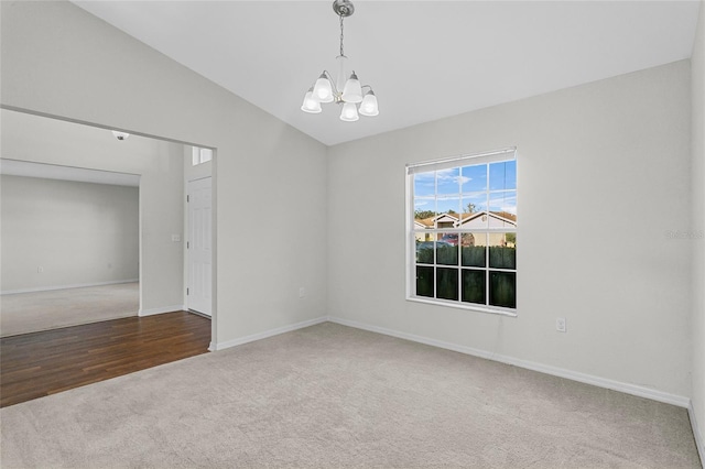 empty room with an inviting chandelier, lofted ceiling, and hardwood / wood-style flooring