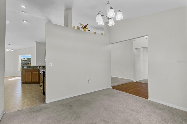 carpeted spare room with an inviting chandelier and vaulted ceiling