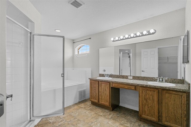 bathroom featuring vanity, a textured ceiling, and separate shower and tub