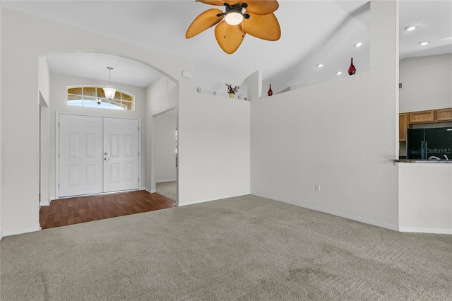 carpeted entryway with high vaulted ceiling and ceiling fan