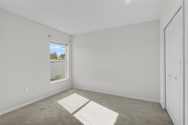 unfurnished bedroom with light colored carpet and a closet