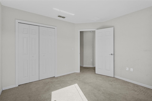 unfurnished bedroom featuring light carpet and a closet