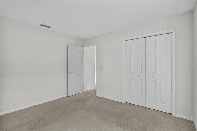 unfurnished bedroom featuring light colored carpet and a closet