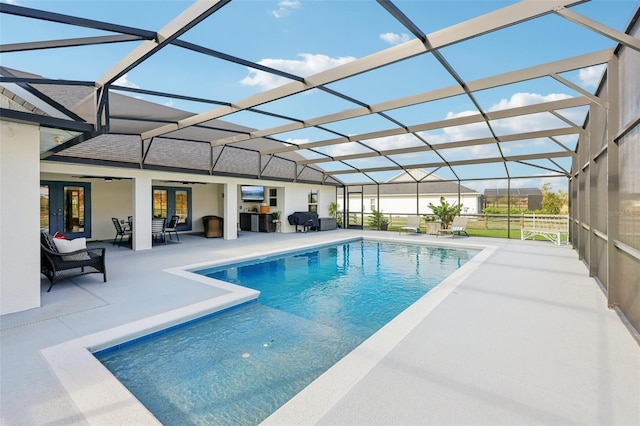 view of pool featuring glass enclosure, a patio area, french doors, and ceiling fan