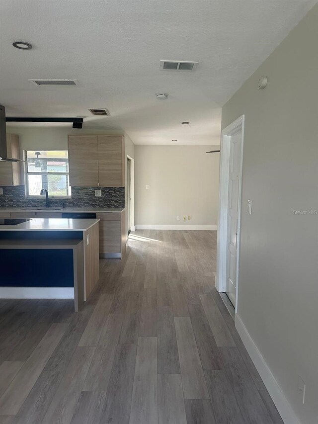 kitchen featuring a center island, dark wood-type flooring, sink, a textured ceiling, and tasteful backsplash