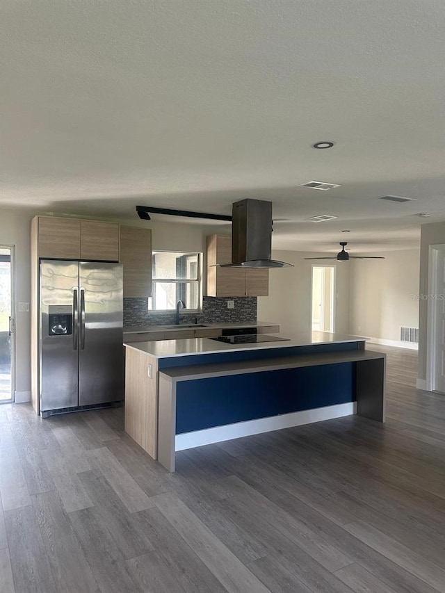 kitchen with stainless steel refrigerator with ice dispenser, light hardwood / wood-style flooring, a wealth of natural light, and exhaust hood