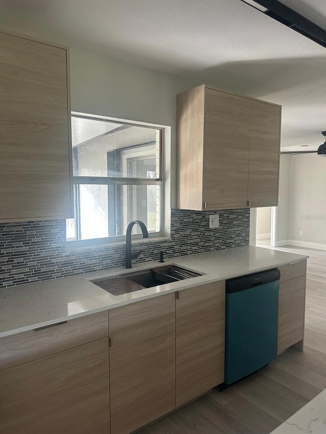 kitchen featuring backsplash, dishwasher, sink, and light hardwood / wood-style flooring