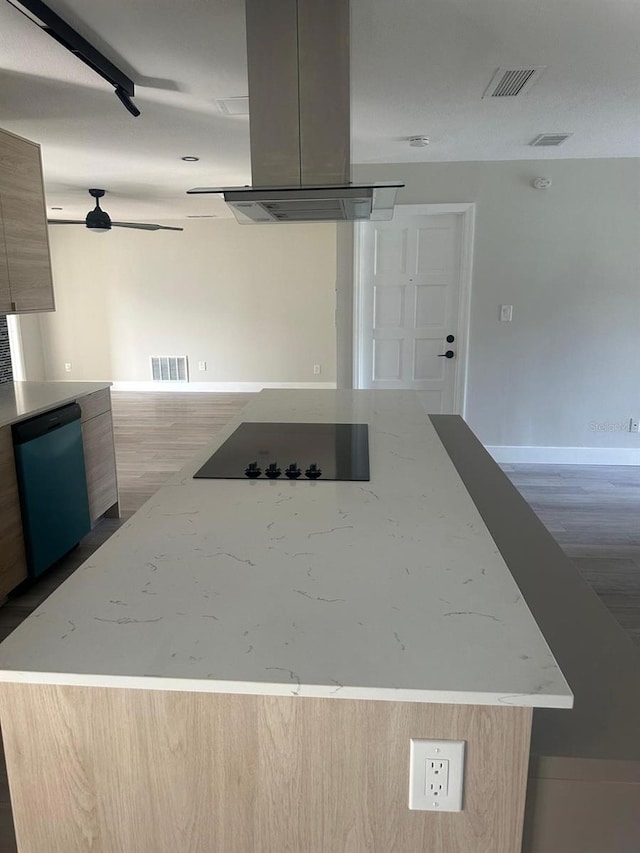 kitchen with light brown cabinets, light stone countertops, black electric cooktop, and island exhaust hood