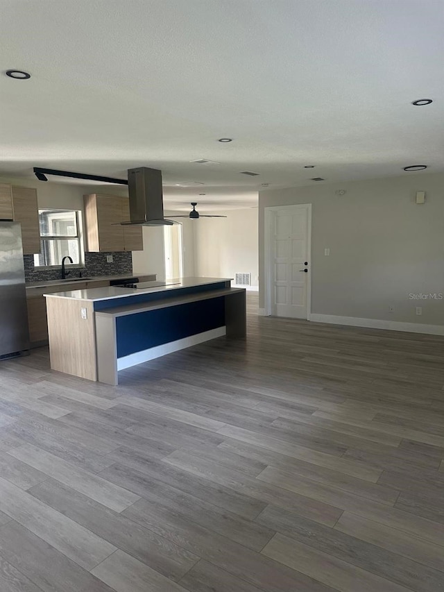 kitchen featuring stainless steel fridge, light wood-type flooring, ventilation hood, and tasteful backsplash