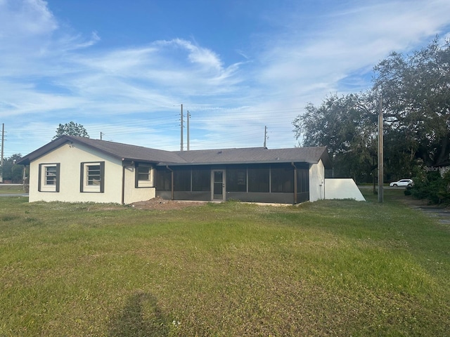 rear view of house with a sunroom and a yard