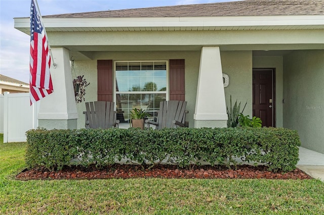 entrance to property with covered porch and a lawn