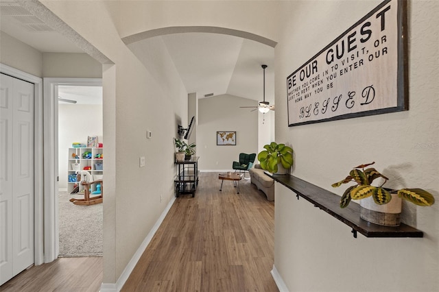 hallway with light hardwood / wood-style flooring and vaulted ceiling