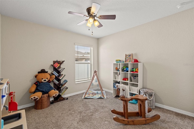 recreation room with carpet flooring, a textured ceiling, and ceiling fan