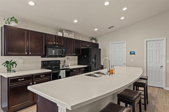 kitchen featuring sink, an island with sink, a breakfast bar area, and black appliances