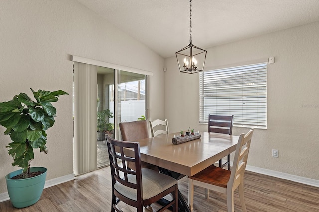 dining room featuring a chandelier, vaulted ceiling, and hardwood / wood-style flooring