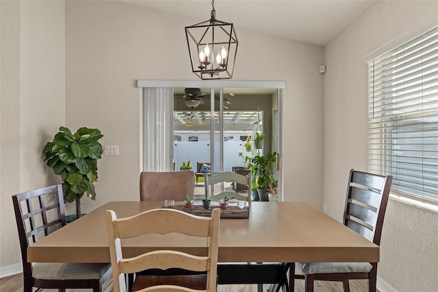 dining room with ceiling fan with notable chandelier, hardwood / wood-style flooring, and lofted ceiling