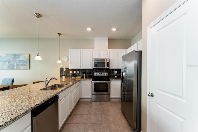 kitchen featuring sink, kitchen peninsula, pendant lighting, white cabinets, and appliances with stainless steel finishes