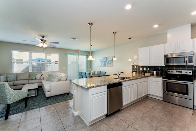 kitchen featuring backsplash, stainless steel appliances, sink, white cabinets, and hanging light fixtures