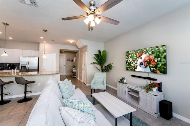 living room with ceiling fan, light tile patterned floors, and a textured ceiling