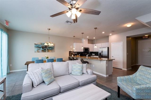 living room with ceiling fan, dark tile patterned floors, and a textured ceiling