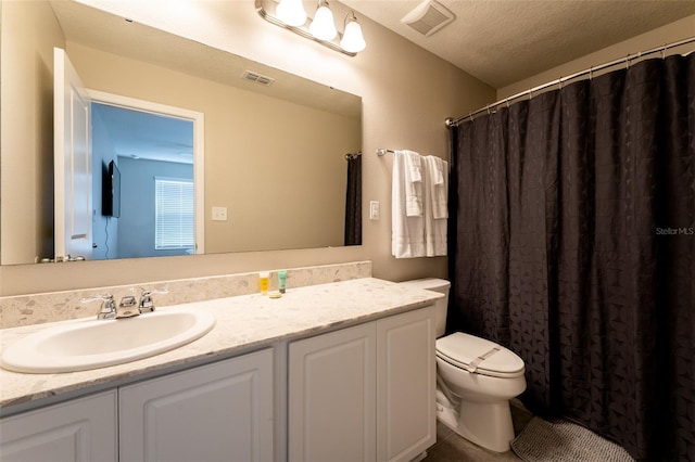 bathroom with vanity, a textured ceiling, and toilet