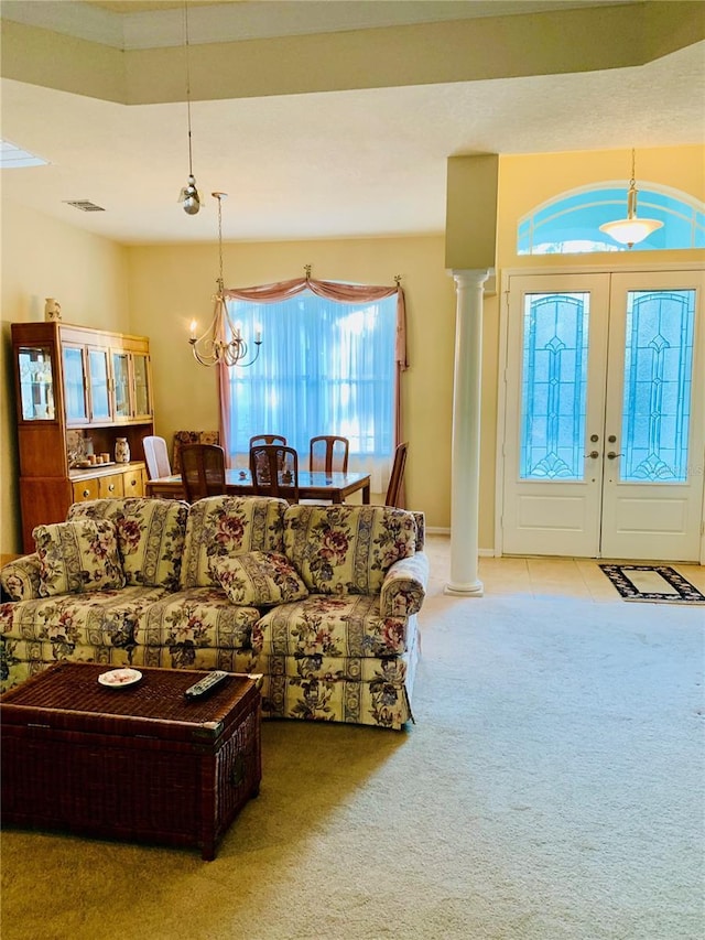 carpeted living room featuring french doors, ornate columns, and a notable chandelier