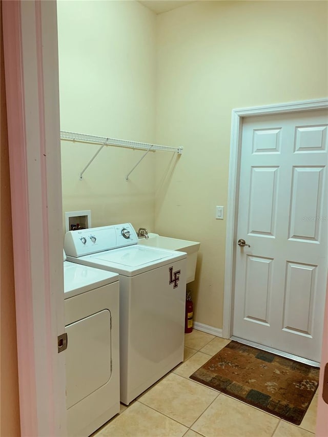 laundry area featuring sink, washing machine and clothes dryer, and light tile patterned floors