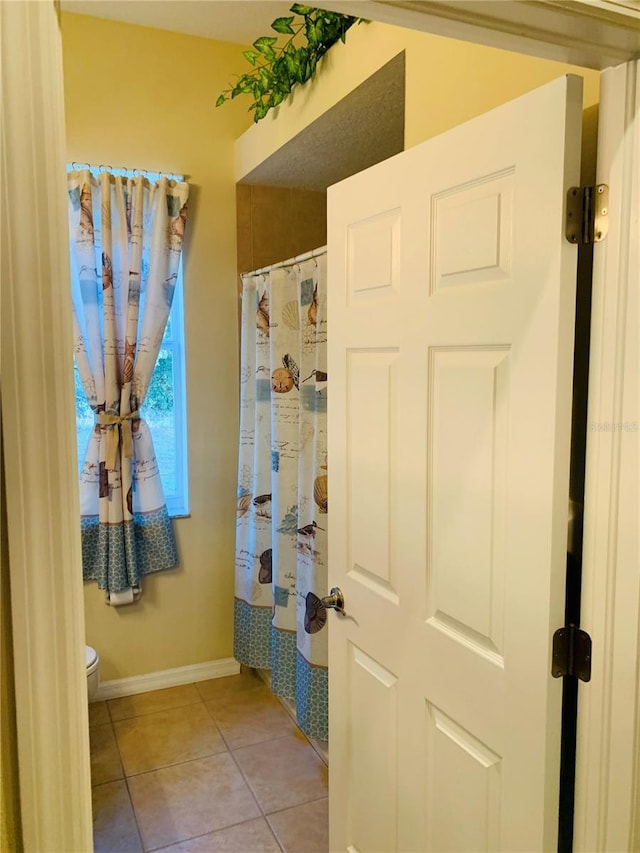 bathroom featuring toilet, a shower with curtain, and tile patterned flooring