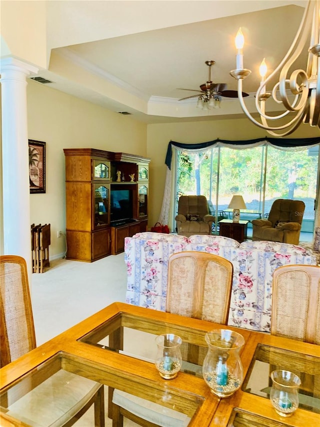 dining space with decorative columns, ceiling fan, and a raised ceiling