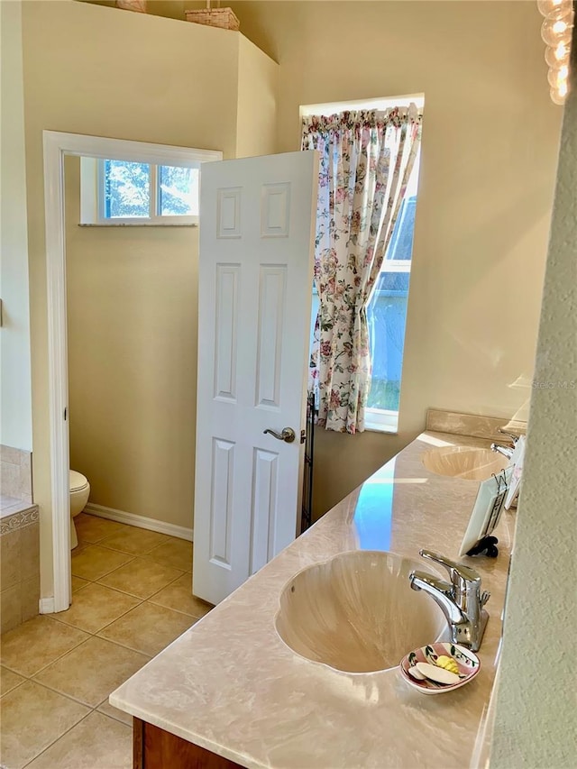 bathroom with vanity, toilet, tiled bath, and tile patterned flooring