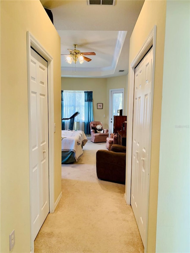 carpeted bedroom featuring ceiling fan, crown molding, and a tray ceiling