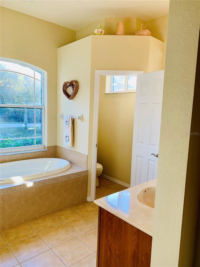 bathroom featuring tiled bath, tile patterned floors, toilet, and vanity