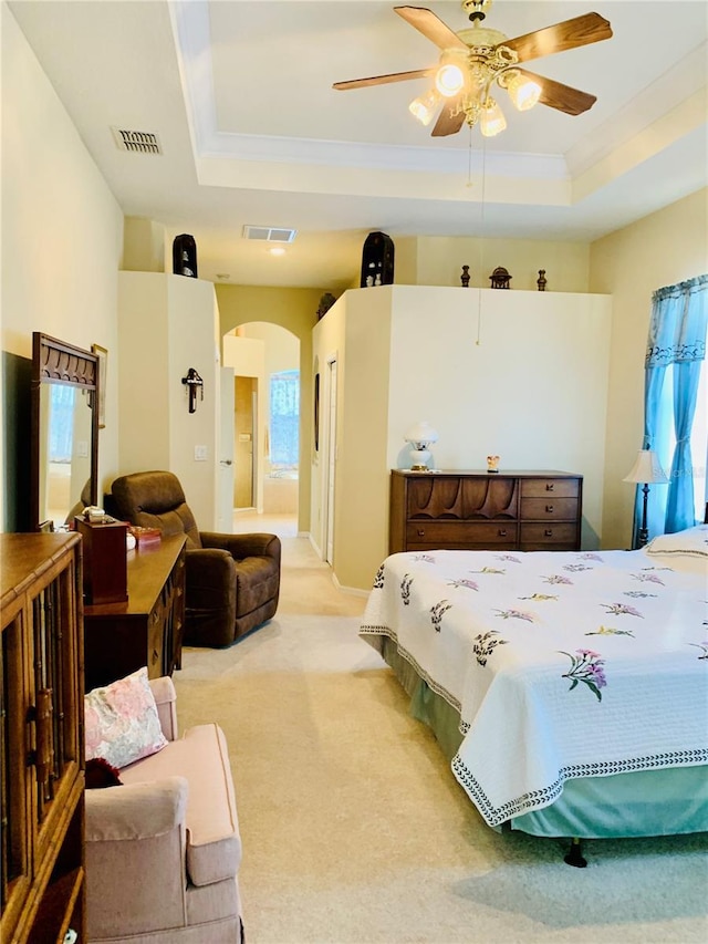 carpeted bedroom featuring ceiling fan, a tray ceiling, and ensuite bathroom