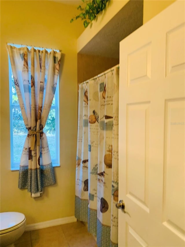 bathroom with toilet, a shower with curtain, and tile patterned flooring