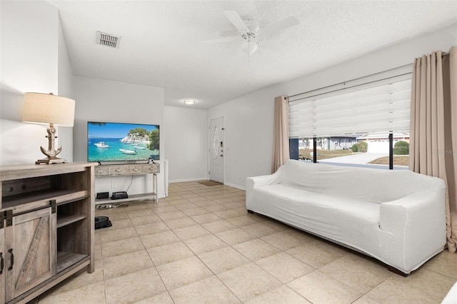 tiled living room with ceiling fan and a textured ceiling